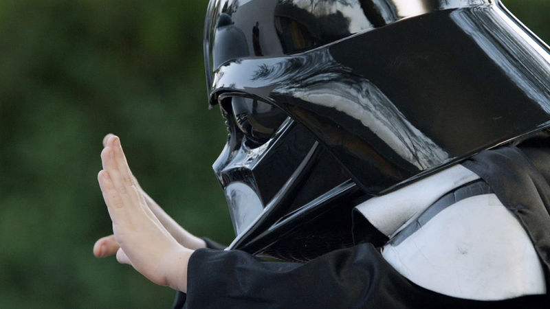 A boy in a Darth Vader mask tries to use magic to move a car.