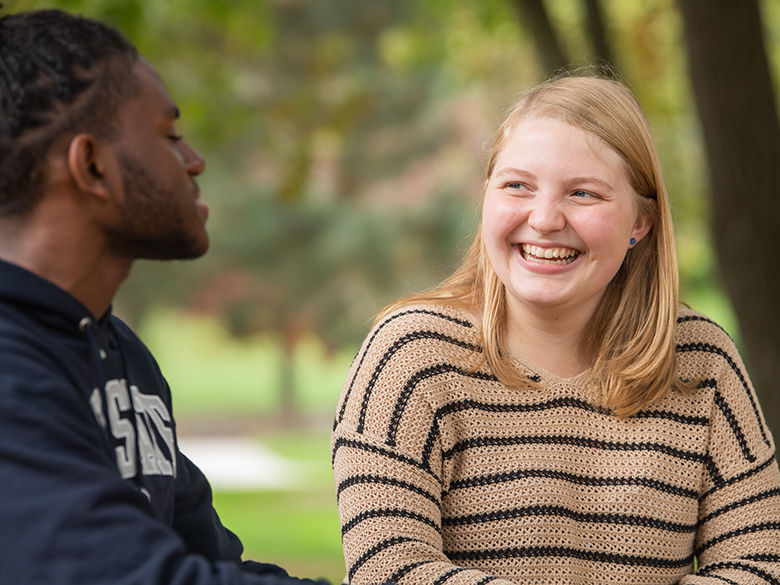 Two students talking on a bench on the Behrend campus