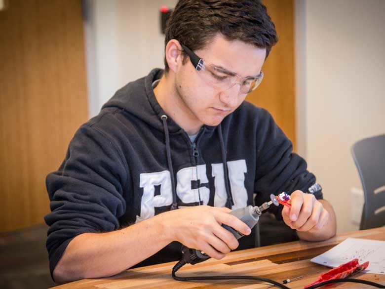 A Penn State Behrend student uses a hand tool.