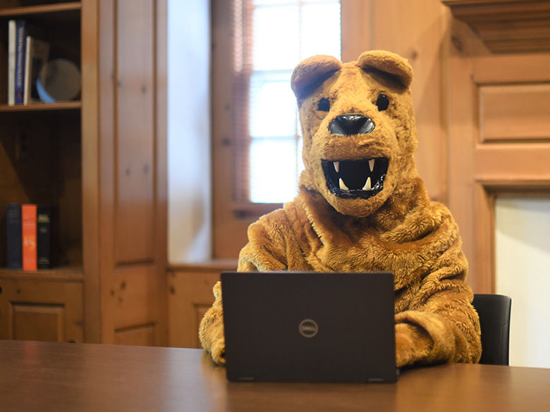 The Behrend Lion types on a laptop computer at a table.