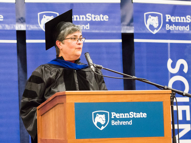 A faculty member wearing academic regalia gives the commencement address.