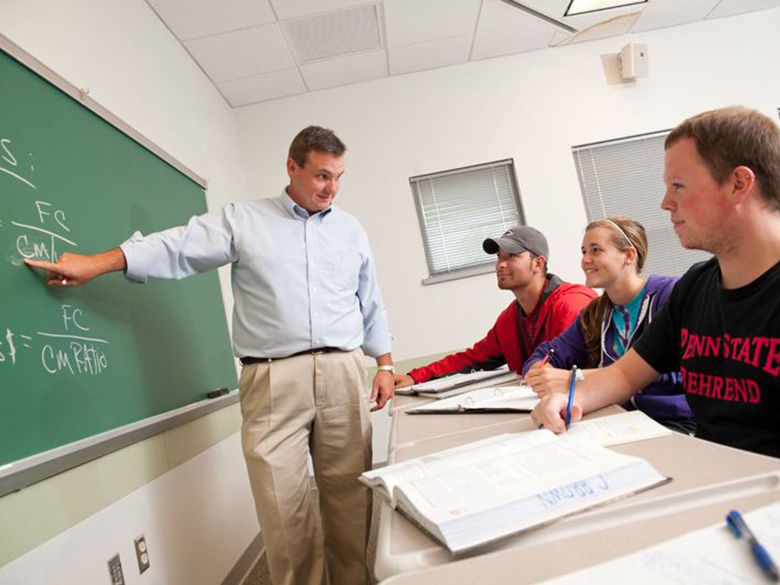 Accounting faculty and students in classroom with figures on chalkboard