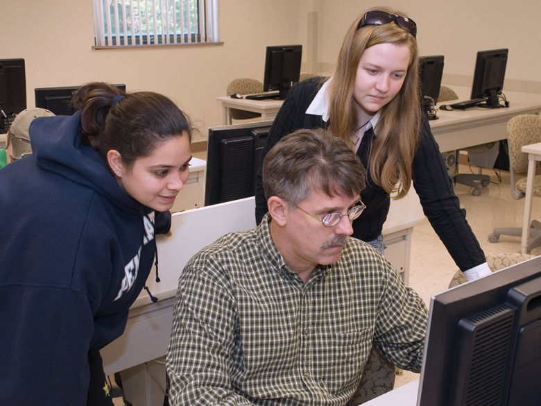 Students and faculty work together at a computer.