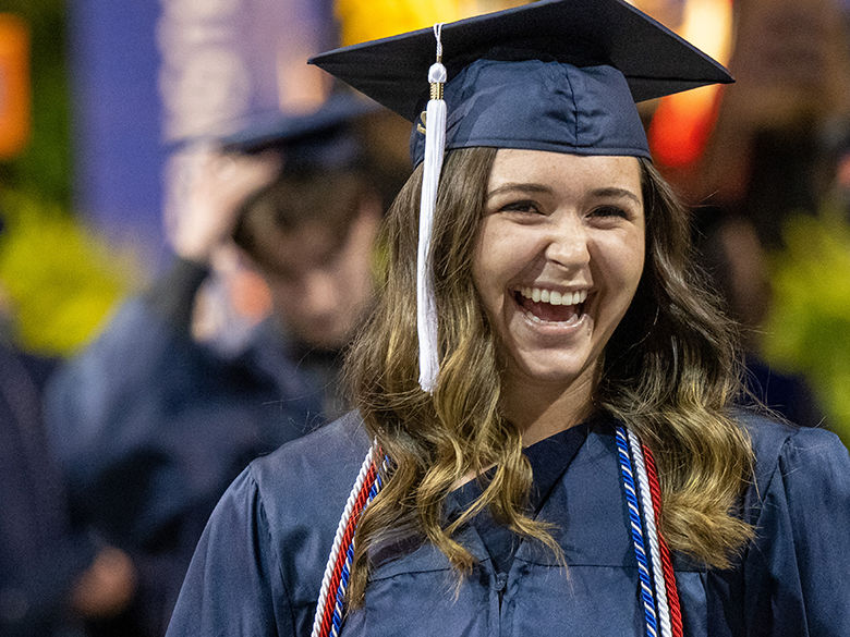 A female graduate smiles after crossing the stage at commencement