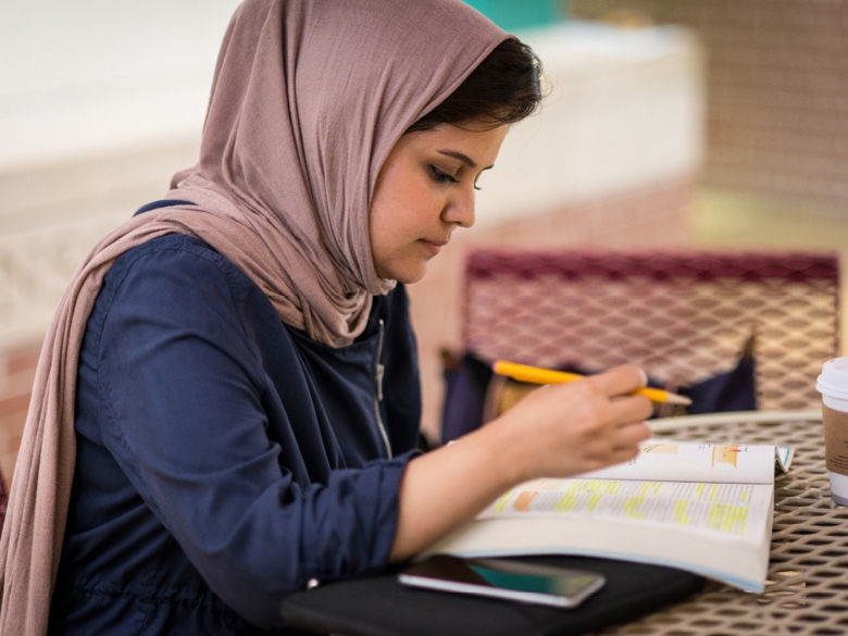 A female student studies a highlighted textbook.