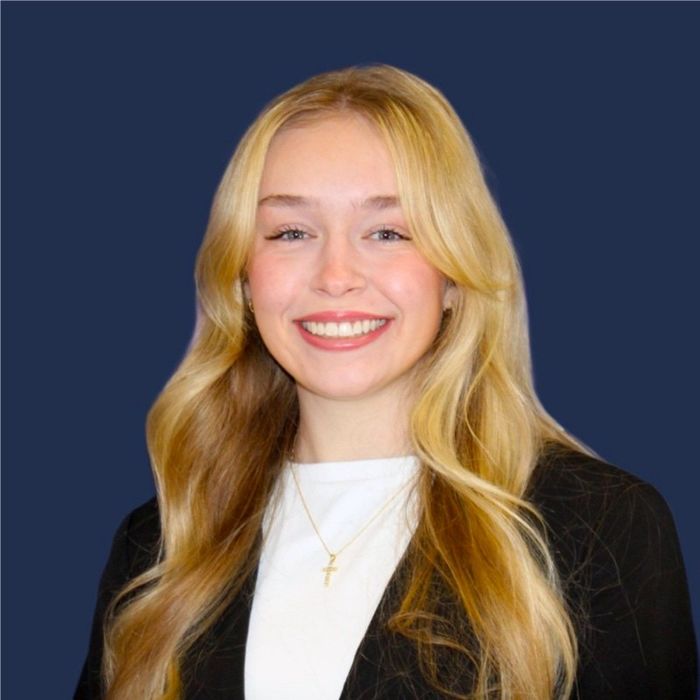 Photo of Lily Pulvino in a black blazer in front of a blue background