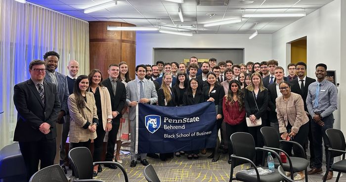Photo of students in business attire holding a Penn State Behrend, Black School of Business banner