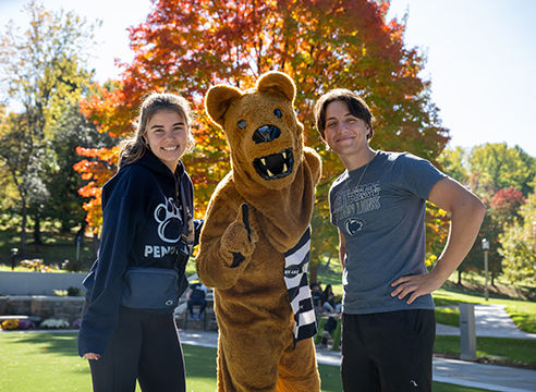 Two Penn State Behrend students, standing with the Nittany Lion mascot in front of Glenhill Gardens
