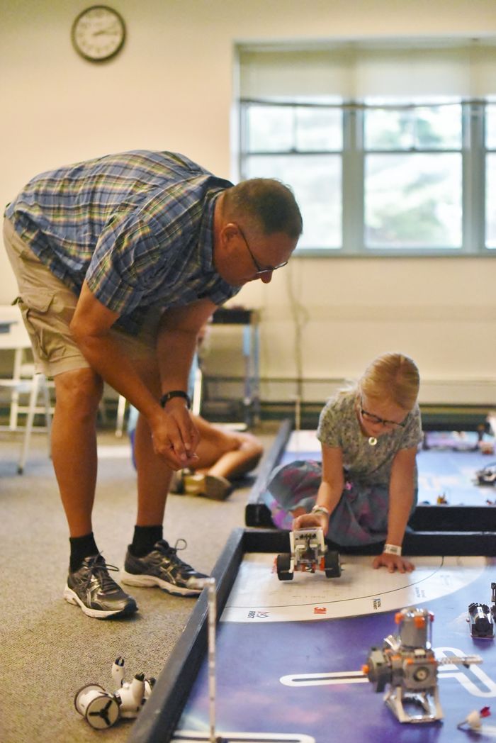 A College for Kids instructor works with a young girl in a Penn State Behrend robotics lab.