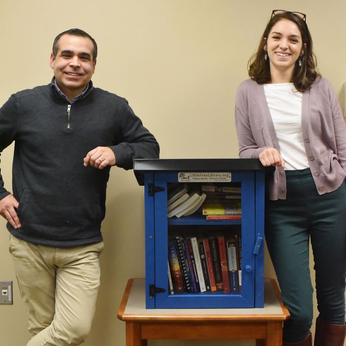 Two Penn State Behrend staff members stand next to one of the college's "Free Little Libraries"