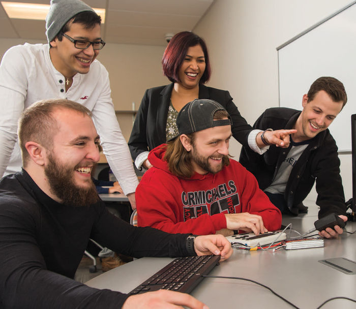 Dr. Shraddha Sangelkar, center, assistant professor of mechanical engineering, is working with engineering students, front row from left, Alec Hydock and Anthony Walker, and second row from left, Marco Nunez and William Aldridge, to reduce the manufacturing costs of a braille reader to make it more accessible to those in developing countries.