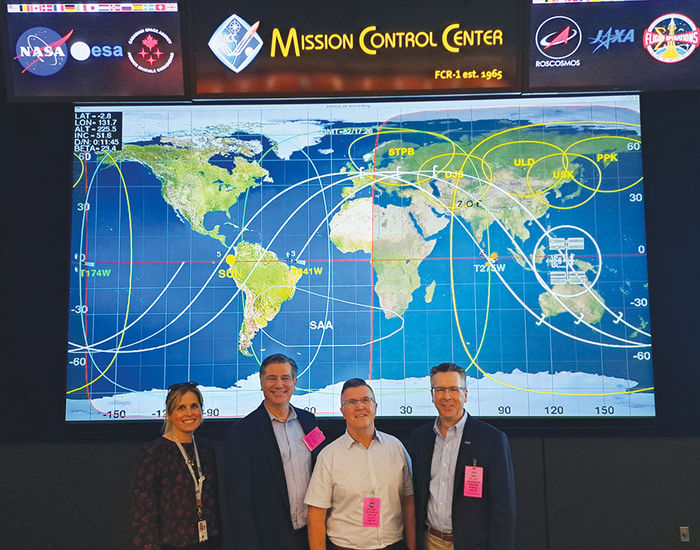 From left, Mary (Good) Lawrence, Tim Kurzweg, Dave Johnson, and Chancellor Ford in front of a world map at NASA’s Johnson Space Center.