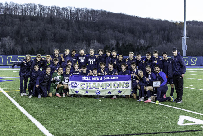 The Penn State Behrend men's soccer team poses with the AMCC championship banner.