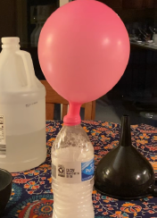 Balloon inflating over lid of water bottle filled with vinegar and baking soda