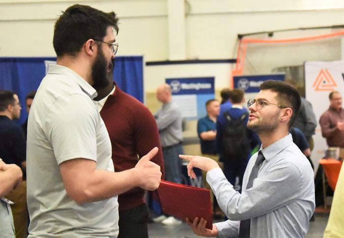 A student gestures while talking with a recruiter at Penn State Behrend's spring Career and Internship Fair.