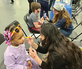 A table and painted faces at the college’s popular STEAM Fair