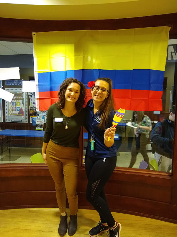 Two women in front of Colombian flag.