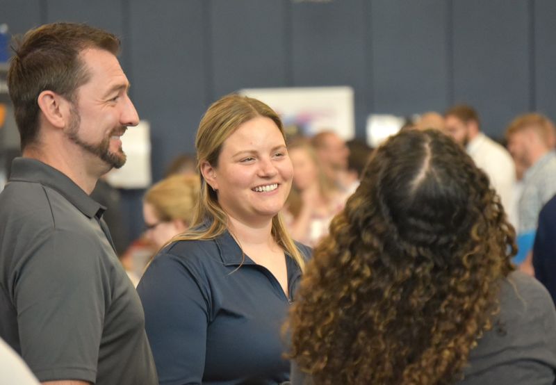 Two recruiters smile while talking with students at Penn State Behrend's career fair.