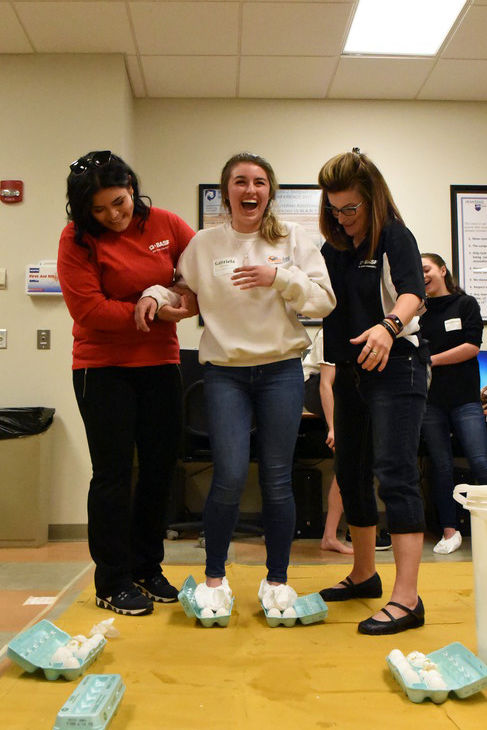 Gabriella McAllister, a seventh-grade student at Erie First Christian Academy, stands on eggs during the “Walking on Egg Shells” activity at Math Options Career Day.