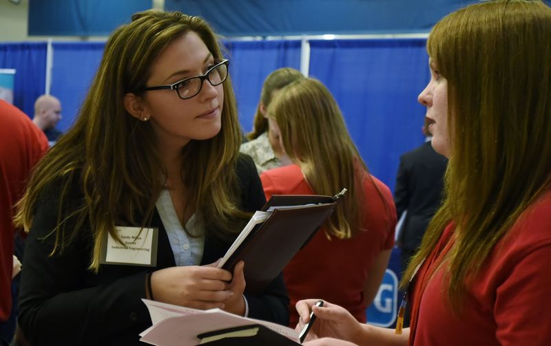 Female student talking to recruiter at job fair.