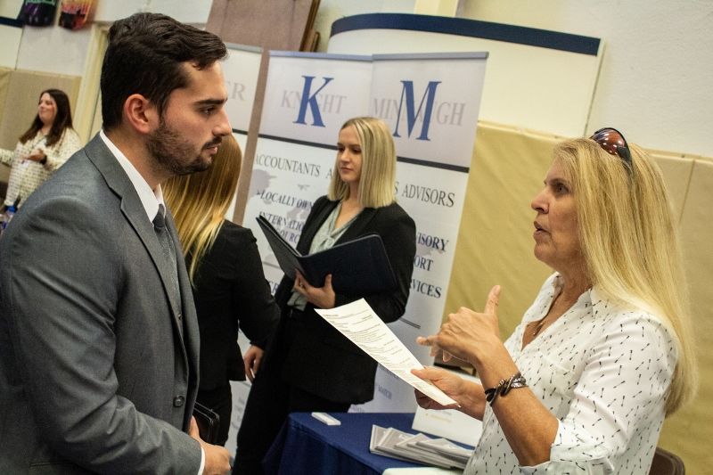A student talks with a corporate recruiter at the Penn State Behrend fall Career and Internship Fair.