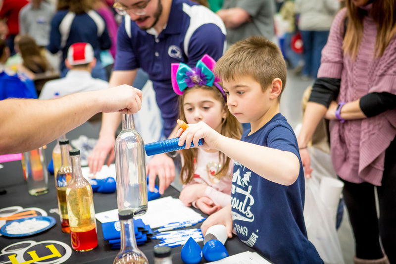 Children experiment with magnets and glass at the Penn State Behrend STEAM fair.