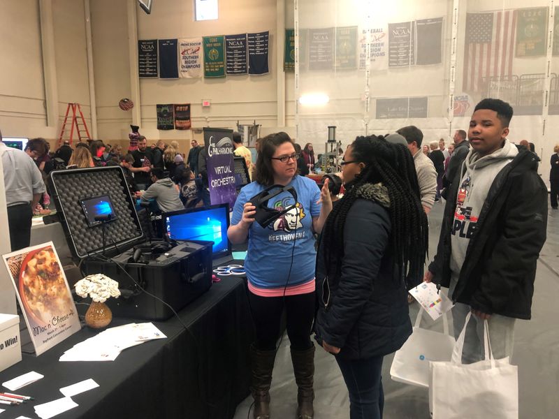 Lisa Herring, director of marketing for the Erie Philharmonic, readies virtual reality goggles for Dalayah McCullum and LeDanian McCullum. The Erie Philharmonic was one of 75 exhibitors to attend the fifth-annual STEM Fair at Penn State Behrend.