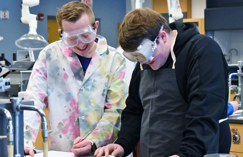 Two students wearing safety goggles conduct a chemistry experiment at Penn State Behrend