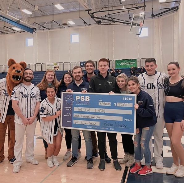Dance and cheer teams holding a giant check for $7,000 to be donated to THON