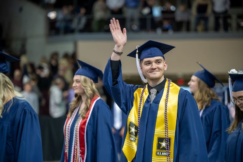 A graduate waves during the procession at Penn State Behrend's spring commencement program.