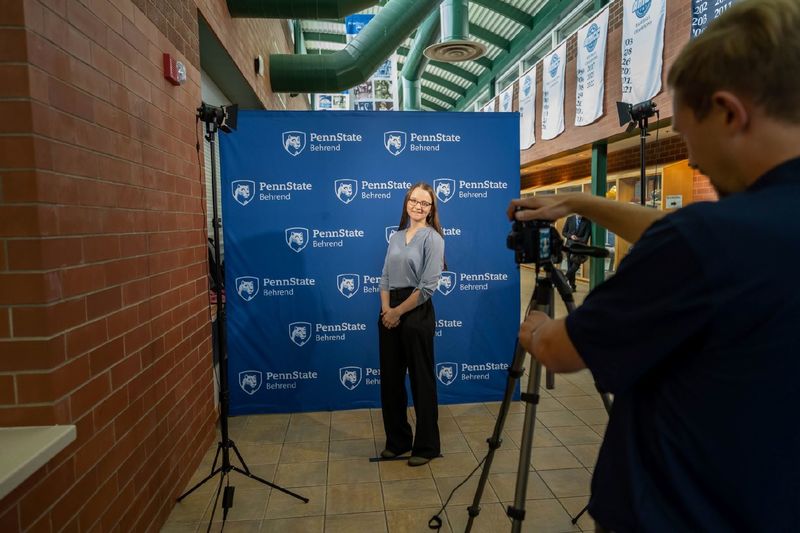 A student photographs another student in front of a professional backdrop at Penn State Behrend's fall career fair.