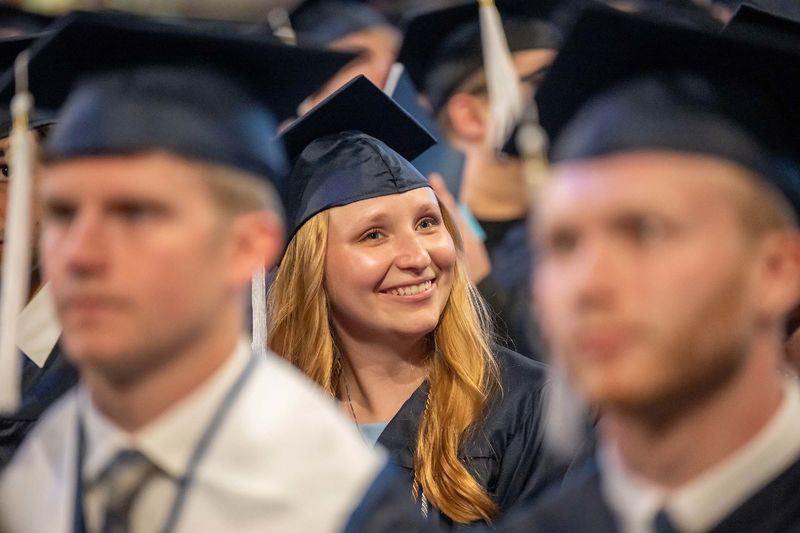 A female graduate smiles in her seat at Penn State Behrend's spring commencement ceremony.