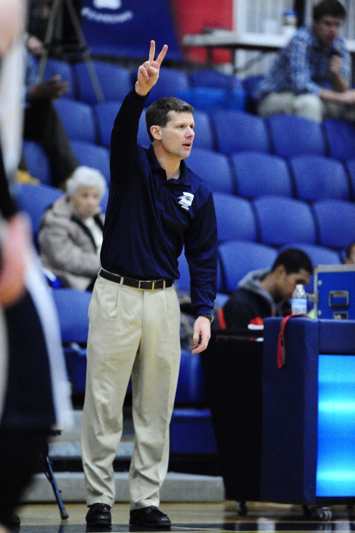 Penn State Behrend men's basketball coach Dave Niland signals to his team from the edge of the court.