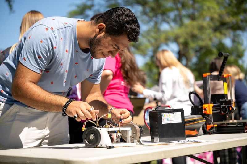 A student works on an electrical device on a table at the Discovery Fair at Penn State Behrend.