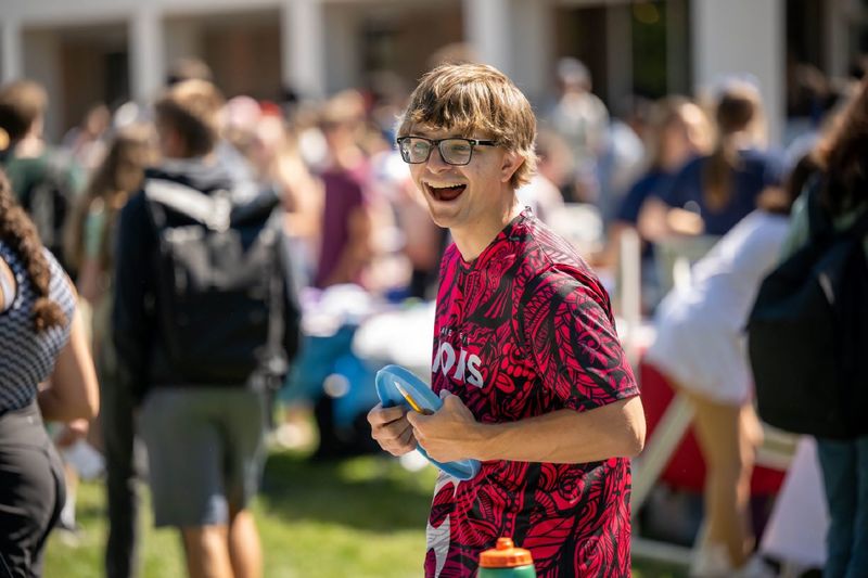 A male student laughs while holding a Frisbee at Penn State Behrend's Discovery Fair.