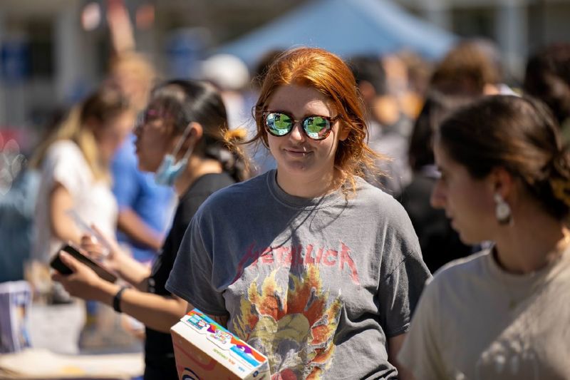 A female student in reflecting sunglasses looks at displays at Penn State Behrend's Discovery Fair.