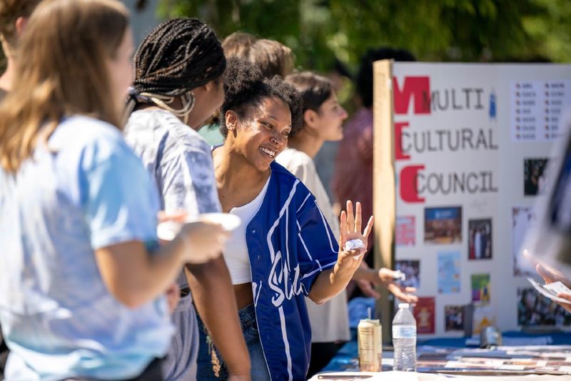 A group of female students laughs while talking at a table at Penn State Behrend's Discovery Fair.