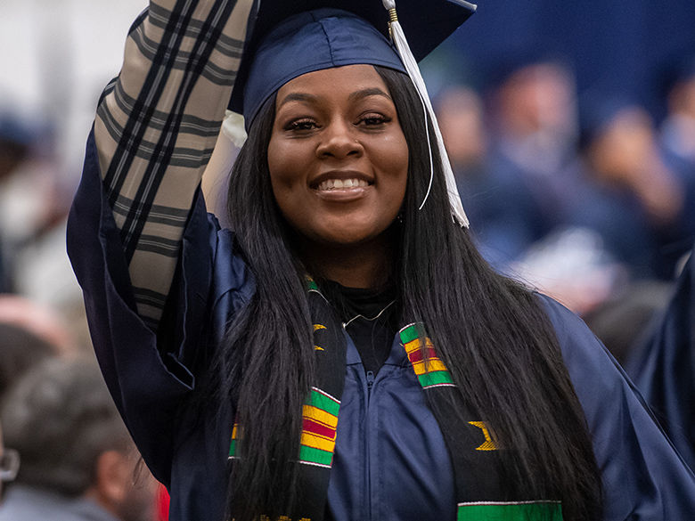 Black female student waves at commencement.