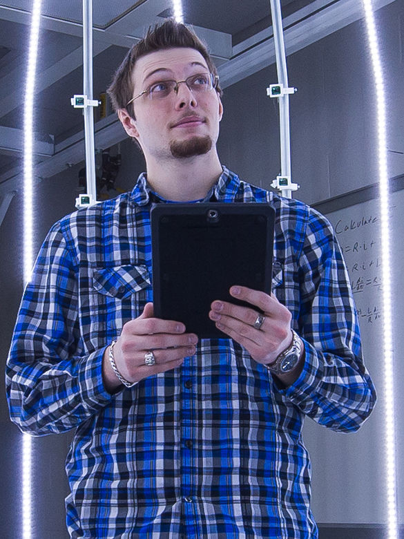 Student holds tablet while standing in life-size 3D scanner.
