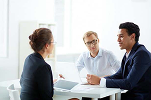Two men and one women sitting at a desk talking