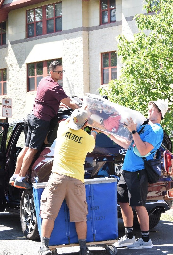 Students help a parent move items from a car during Penn State Behrend's move-in day.
