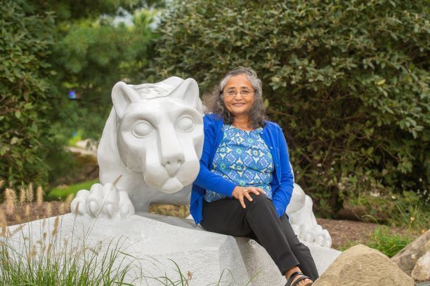 Alumna Nishi Gupta sits at the Nittany Lion shrine at Penn State Behrend