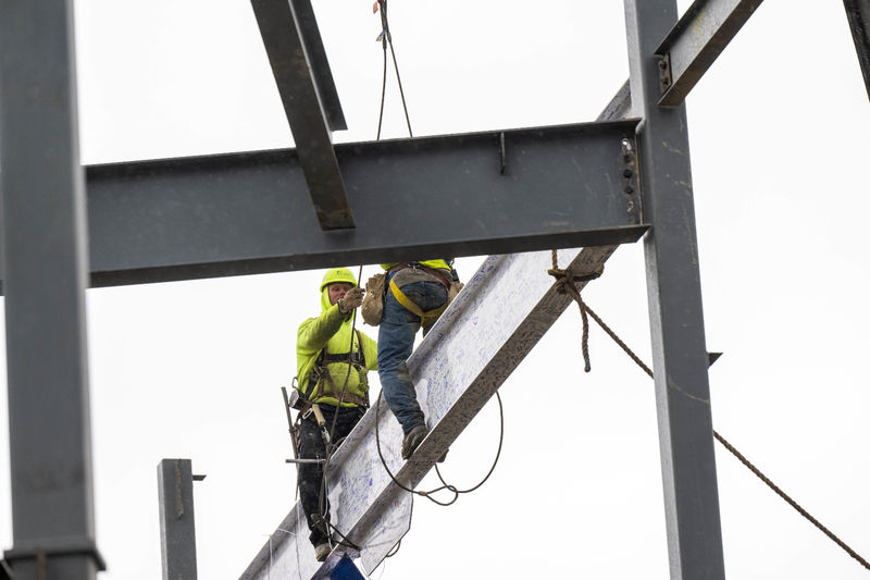 Two steelworkers set a beam in place at the site of Penn State Behrend's new Erie Hall.