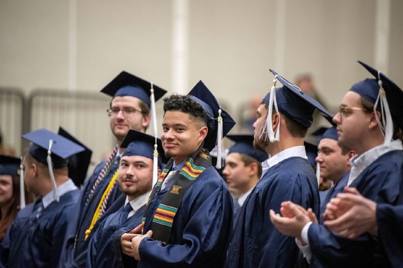 New graduates smile and applaud during Penn State Behrend's fall 2022 commencement program.