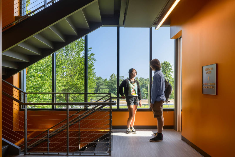 Two students talk on a stairway landing in Penn State Behrend's Federal House.