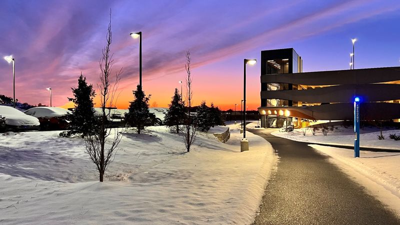 A parking garage with a purple and pink winter sunset behind it