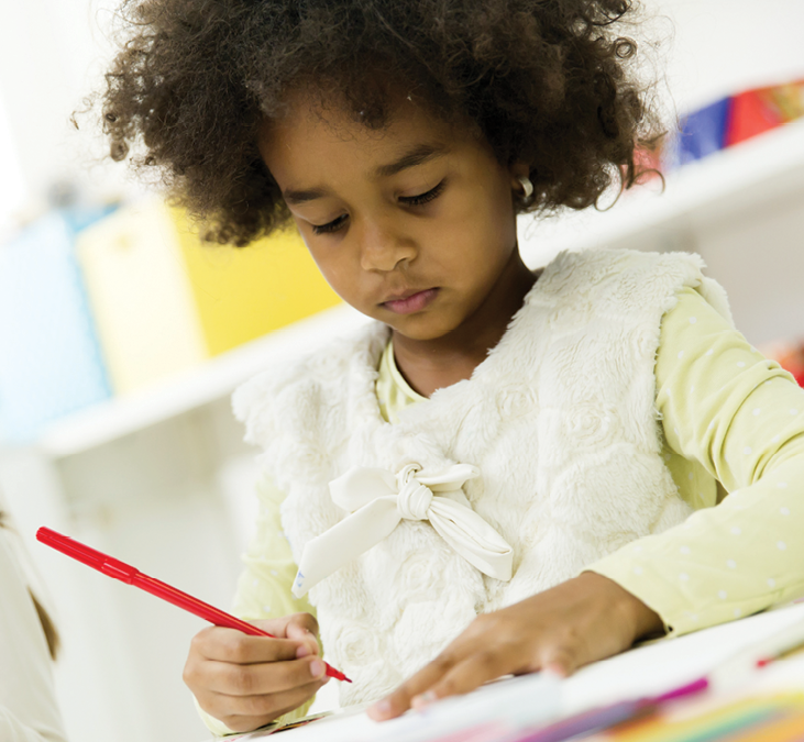 A child is drawing on paper with a marker