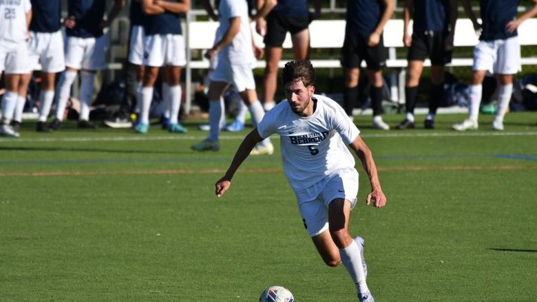 A Penn State Behrend men's soccer player advances the ball up midfield.