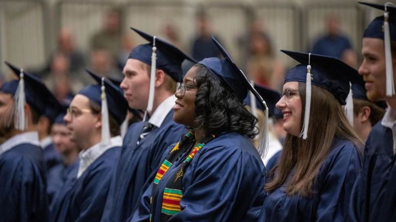 A row of graduates in caps and gowns listen to a speaker during Penn State Behrend's fall 2022 commencement program.