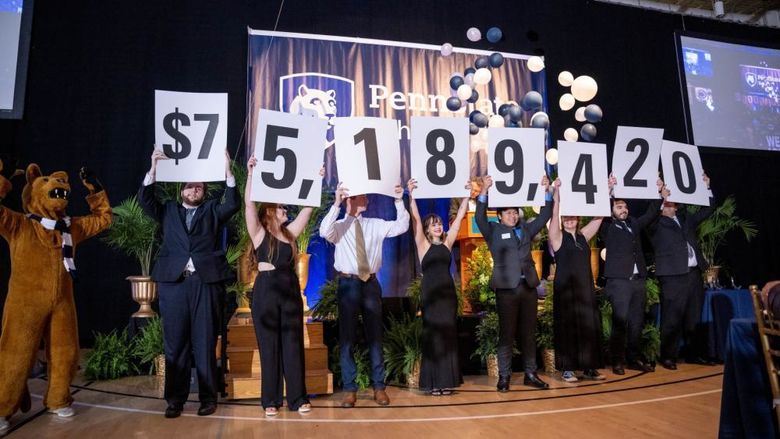 A row of Penn State Behrend students hold up placards with numbers that show the fundraising total in the college's six-year campaign.